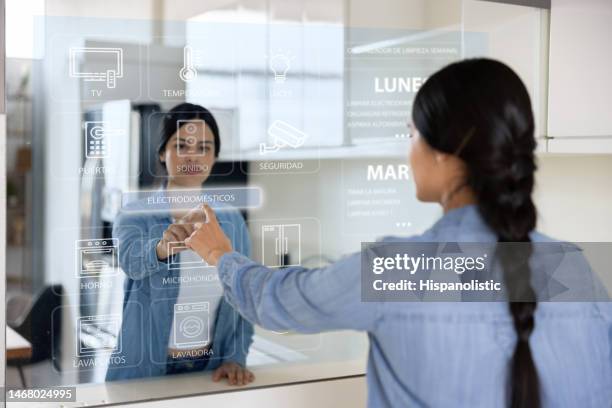 woman programing the appliances using an interactive screen at her smart home - future home technology stock pictures, royalty-free photos & images