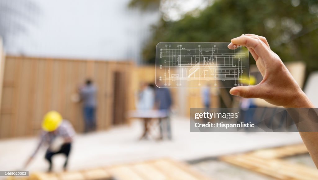 Architect at a construction site looking at a blueprint using an interactive screen
