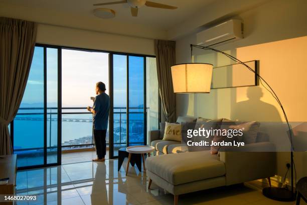 man having coffee during sunrise at balcony overlook the sea - balcony stock photos et images de collection