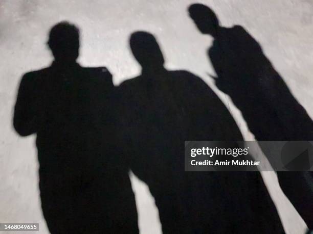 shadows of three friends standing against gray ground. - ombra in primo piano foto e immagini stock