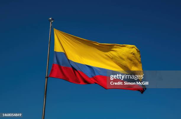 colombian national flag billowing from a flagpole on a sunny day - colombia pattern stock pictures, royalty-free photos & images