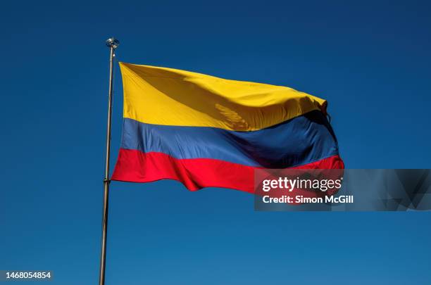 colombian national flag billowing from a flagpole on a sunny day - colombia photos et images de collection
