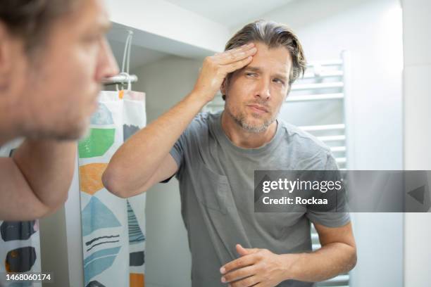 handsome man applying moisturizer to his face - men facial stock pictures, royalty-free photos & images