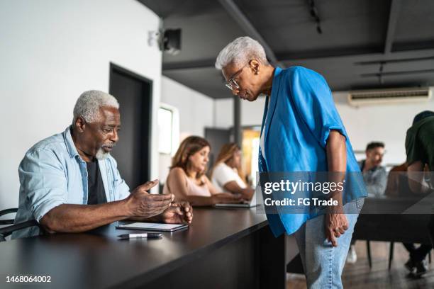 senior woman helping senior man during class or seminar - self development stock pictures, royalty-free photos & images