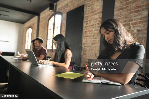 mid adult woman taking notes during class or seminar - college admissions stock pictures, royalty-free photos & images