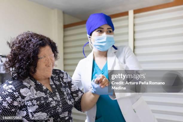 doctor helping her patient back on her feet - blue face mask stock pictures, royalty-free photos & images