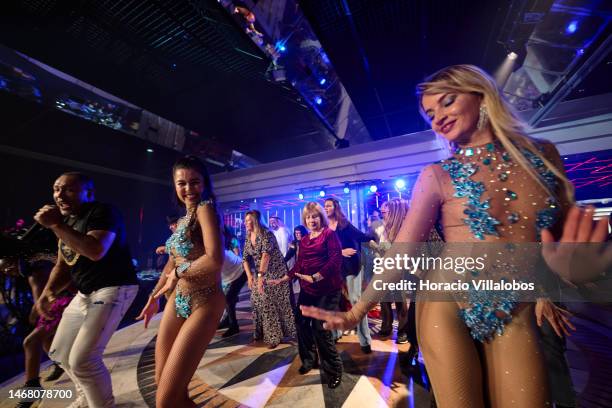 Revelers dance with members of Brazilian Banda Toque de Classe during its performance of carnival rhythms in Lounge D of Estoril Casino on February...