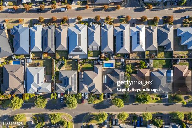 aerial view  directly above new rural housing development, mostly grey roofing, some green landscaping, trees, orange-coloured street trees. - property boundary stock pictures, royalty-free photos & images