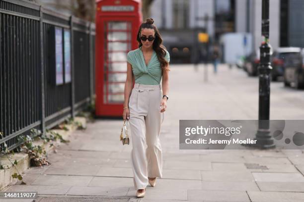 Tamara Kalinic seen wearing a Valentino bag, beige wide leg pants, a green shirt, beige heels, a Cartier love bracelet with diamonds, an Audemar...