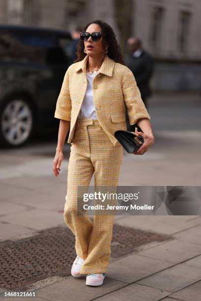 Fashion week guest seen wearing dark shades, a yellow matching set with a blazer and wide leg pants, white sneakers, a white shirt and a black bag...