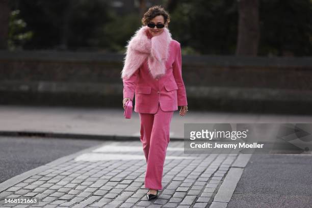 Fashion week guest seen wearing a pink look with a fluffy sweater, a pink blazer, pink pants, a matching pink JW Anderson mini bag, black Miu Miu...
