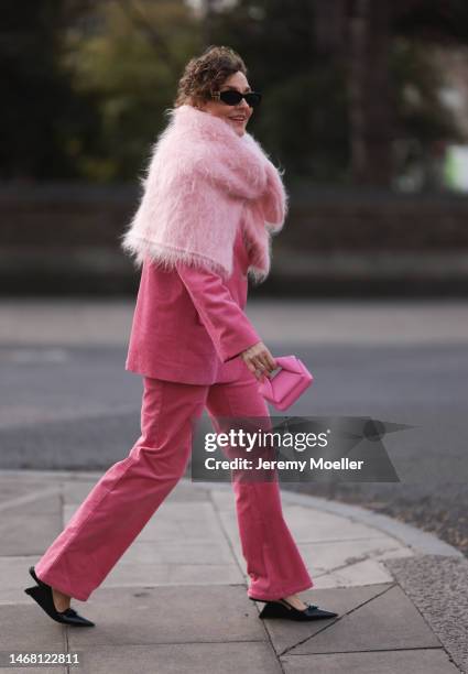 Fashion week guest seen wearing a pink look with a fluffy sweater, a pink blazer, pink pants, a matching pink JW Anderson mini bag, black Miu Miu...