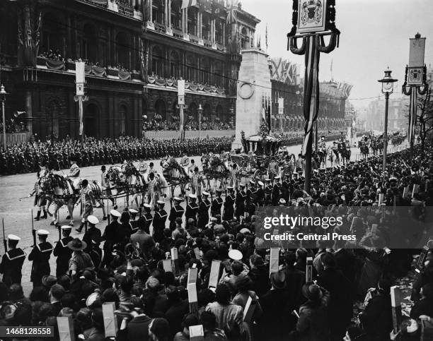 People in the crowd use cardboard periscopes to catch a glimpse of the Gold State Coach, in which George VI and Queen Elizabeth are riding, during...