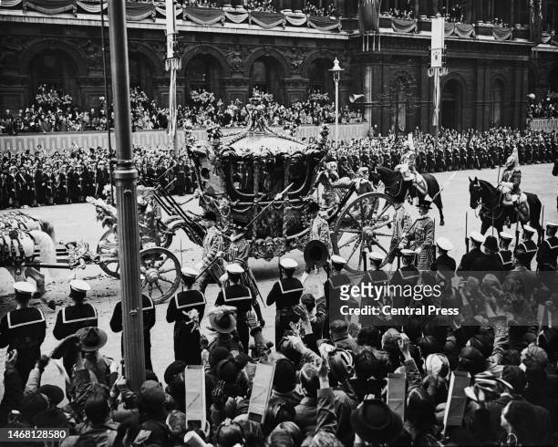 People in the crowd use cardboard periscopes to catch a glimpse of the Gold State Coach, in which George VI and Queen Elizabeth are riding, during...