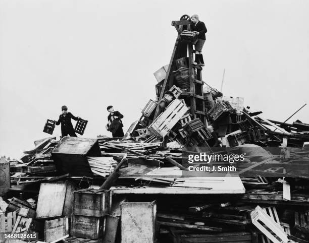 Children building a bonfire out of rubbish, such as wooden crates, to be burned in celebration of the Coronation of George VI and Elizabeth, in...
