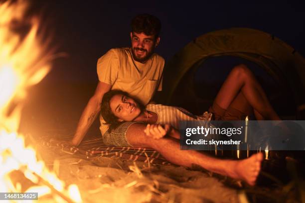 happy couple relaxing on camping by night. - camp fire stock pictures, royalty-free photos & images