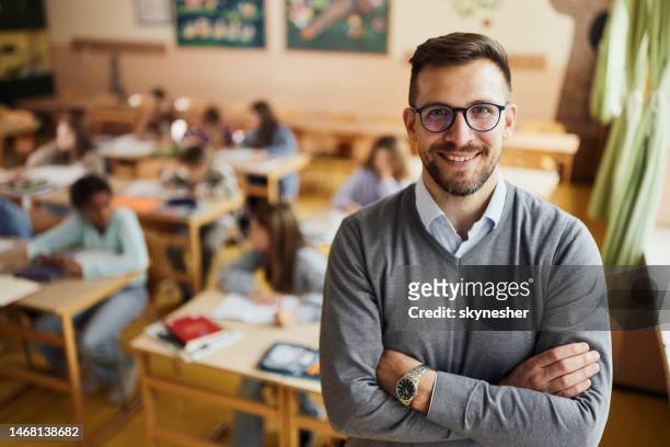 happy elementary teacher in front of his students in the classroom. - professor imagens e fotografias de stock