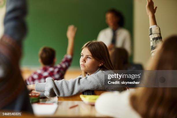 nachdenkliche schülerin unter ihren klassenkameraden in der grundschule. - schulkinder stock-fotos und bilder