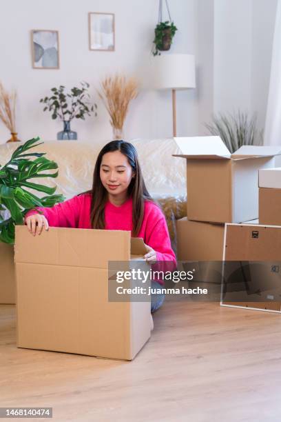 smiling asian woman unpacking boxes - new content stock pictures, royalty-free photos & images