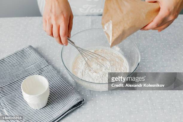 a woman pours gluten-free flour into a glass bowl. the process of preparing healthy pastries. gluten free diet - suikervrij stockfoto's en -beelden