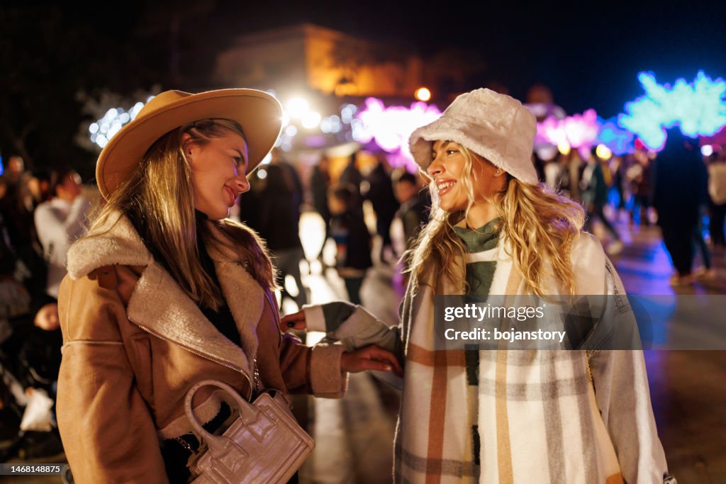 Cheerful female friends having fun in amusement park in the evening