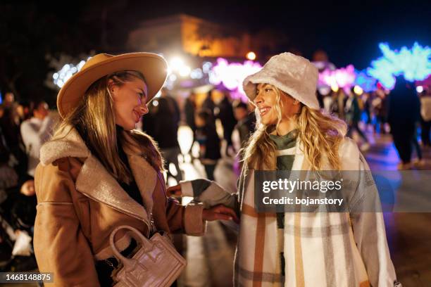 cheerful female friends having fun in amusement park in the evening - christmas concert stock pictures, royalty-free photos & images