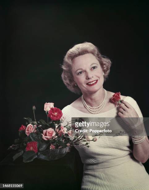English actress, singer and dancer Anna Neagle posed with an arrangement of roses, London, 28th September 1957.
