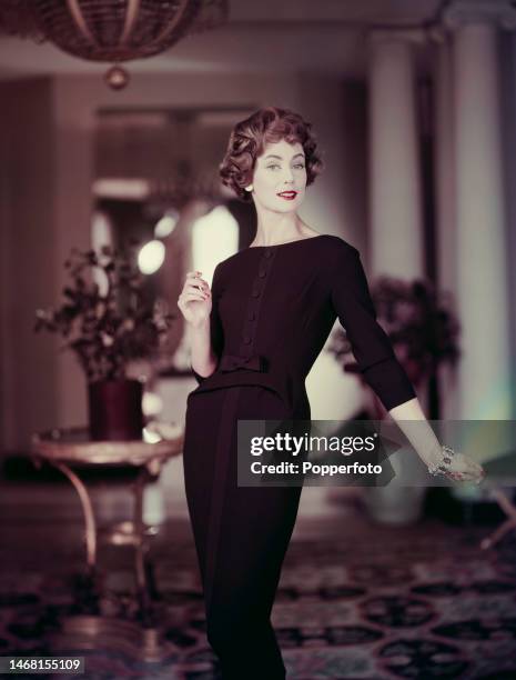Female fashion model wears a little black dress, the dress is a collarless sheath style with a contrasting satin panel down the centre front and a...