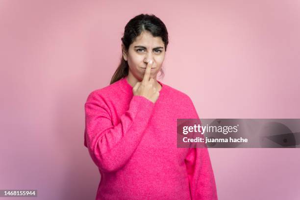 young woman showing bad smell gesture in studio - pink colour scheme stock pictures, royalty-free photos & images