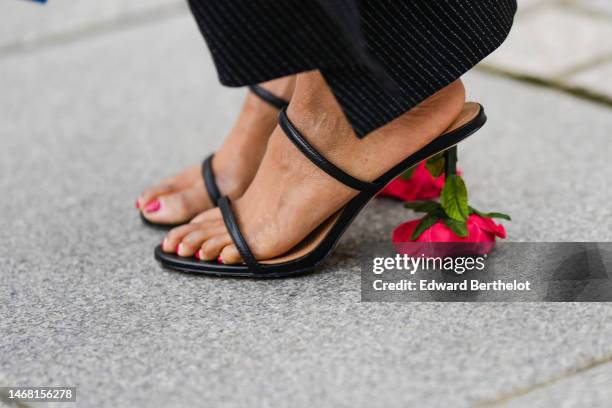 Guest wears a black long midi skirt, black shiny leather strappy / red flower heels mules from Loewe, outside Emilia Wickstead, during London Fashion...