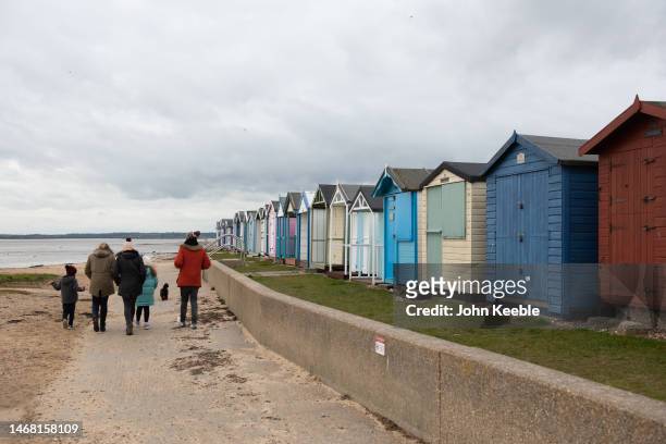 Family walk along the promenade past beach huts on February 18, 2023 in Brightlingsea, England .