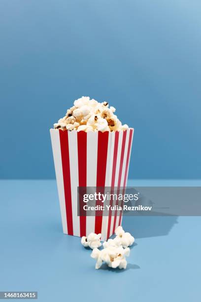 red paper striped bucket with popcorn on the blue background - salted stock pictures, royalty-free photos & images