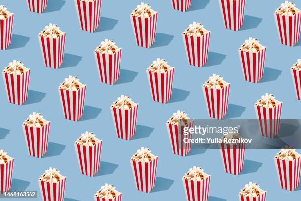 repeated red paper striped buckets with popcorn on the blue background - pop corn stock pictures, royalty-free photos & images