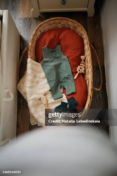 pregnant mother prepares things for newborn. natural wicker basket, wooden rattle and eco cotton clothes for future newborn baby. - empty crib imagens e fotografias de stock