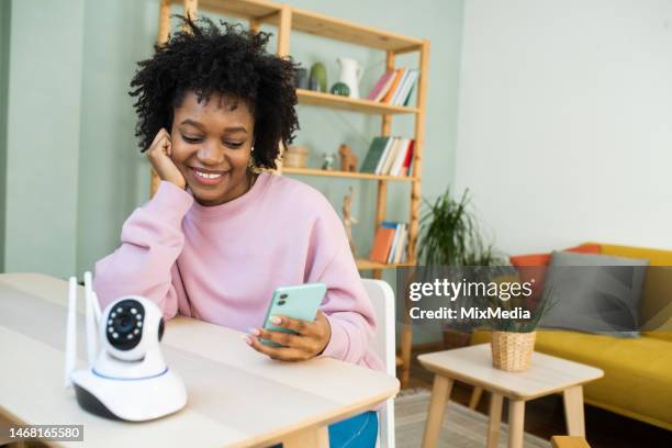 happy woman using smartphone to setup a smart camera - security camera house stock pictures, royalty-free photos & images