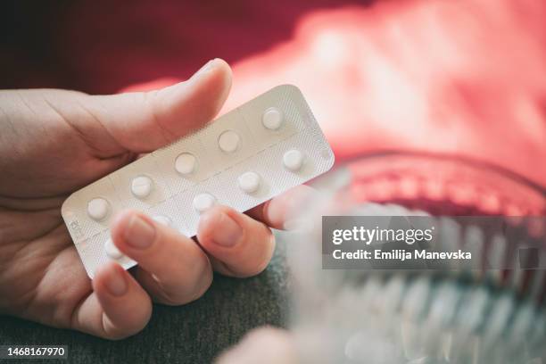 woman taking medicines in hand with a glass of water at home - allergy medicine stock pictures, royalty-free photos & images