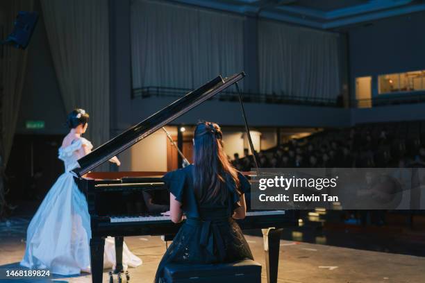 asian chinese pianist playing grand piano with female opera singer performing solo on stage - classical concert stock pictures, royalty-free photos & images