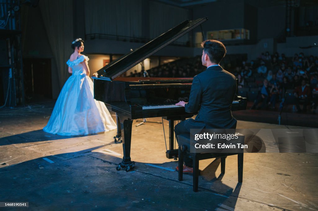 Asian Chinese Pianist playing grand piano with Female opera singer performing solo on stage