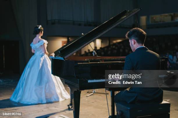 asian chinese pianist playing grand piano with female opera singer performing solo on stage - soprano stock pictures, royalty-free photos & images