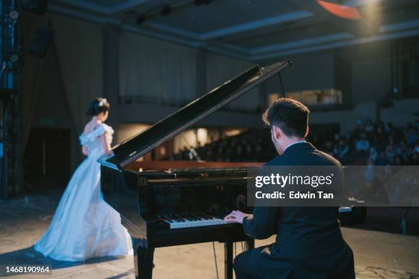 asiatisch-chinesische pianistin spielt flügel mit operns�ängerin, die solo auf der bühne steht - good boy premiere stock-fotos und bilder