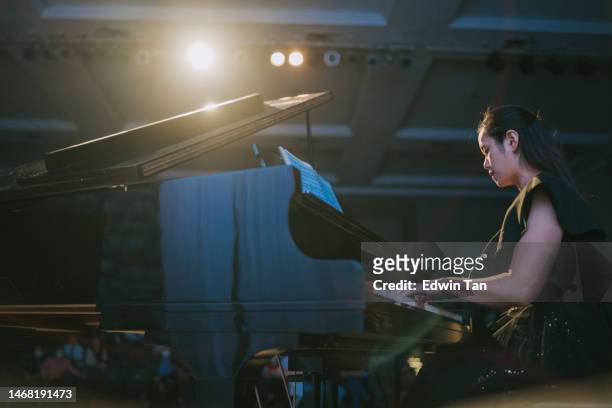 asian chinese female pianist performing solo on stage with grand piano - asian pianist stock pictures, royalty-free photos & images