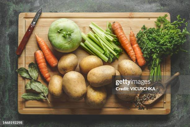 various raw vegetables ingredients for potato soup or vegetable broth on cutting baerd with peeler and seasonings. - fond stockfoto's en -beelden