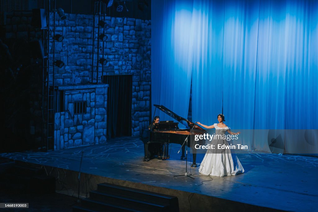Joven cantante de ópera china actuando en solitario en el escenario con pianista frente al público