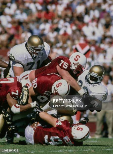 Autry Denson, Running Back for the Notre Dame Fighting Irish is tackled by Carl Hanson, #94 Bryan Werner and Mark Stockbauer, Defensive Linemen for...