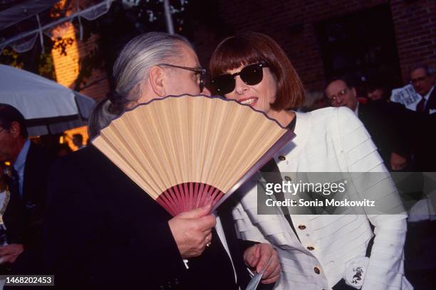 German fashion designer Karl Lagerfeld holds a hand fan as he talks to British-American fashion editor & journalist Anna Wintour attend a Chanel...