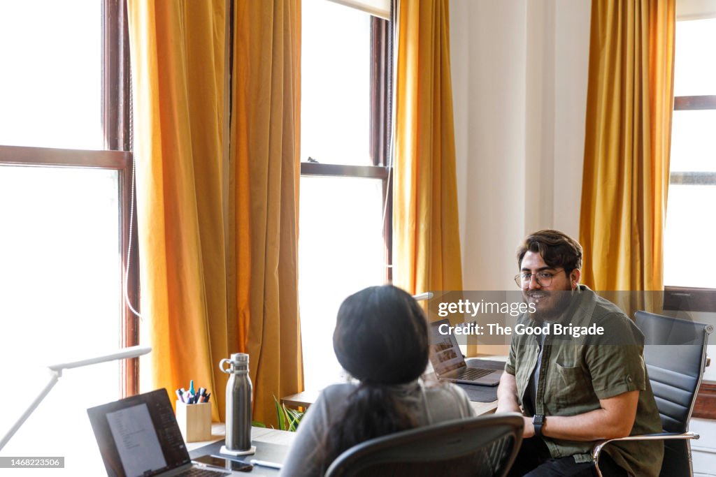 Male and female business colleagues discussing together while sitting in office