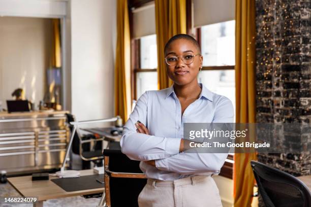 confident female entrepreneur standing with arms crossed at office - black blouse fotografías e imágenes de stock