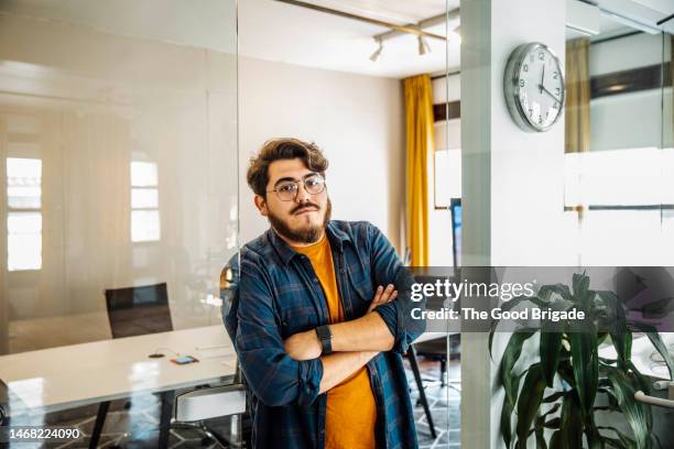 confident businessman with arms crossed leaning on glass wall in office - undone stock pictures, royalty-free photos & images