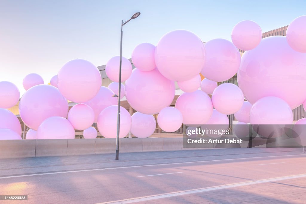 Digital 3D picture of pink balloons levitating and interacting with the city.