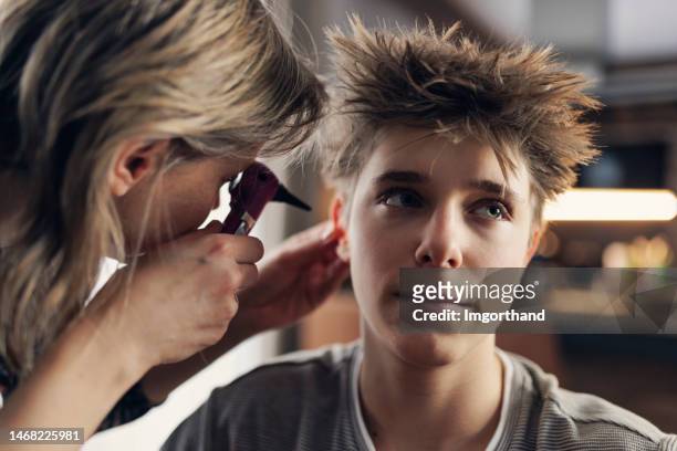 Teenage boy having an ear examination at home